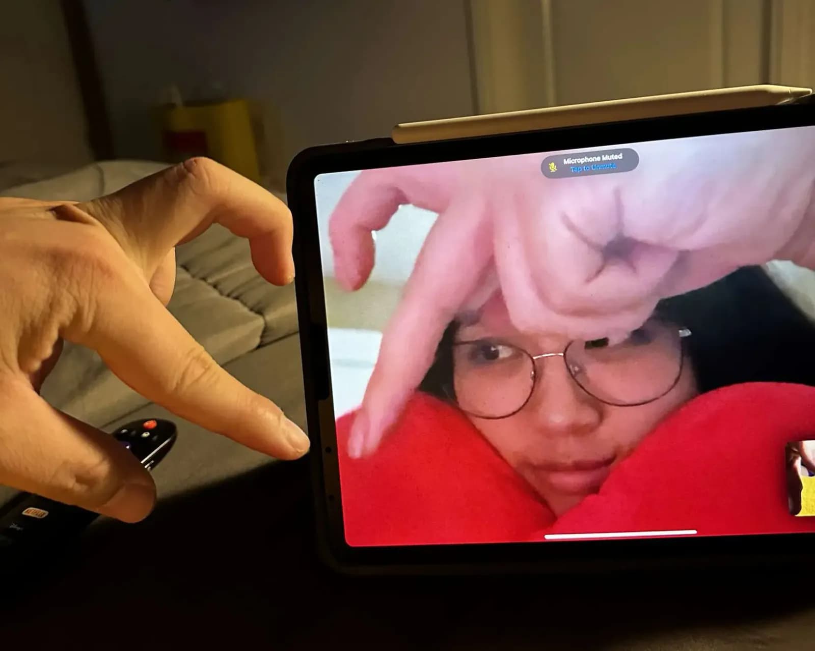 Two hands completing a heart shape across a video call