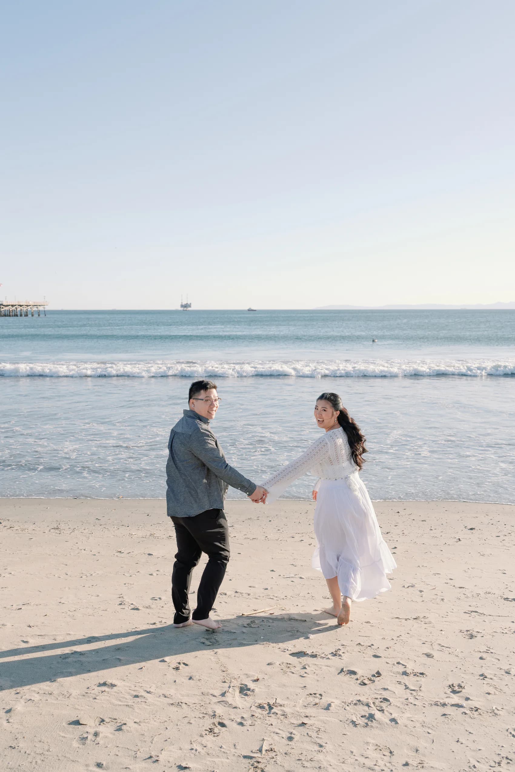 Christine and Thomas smiling back while walking along the beach