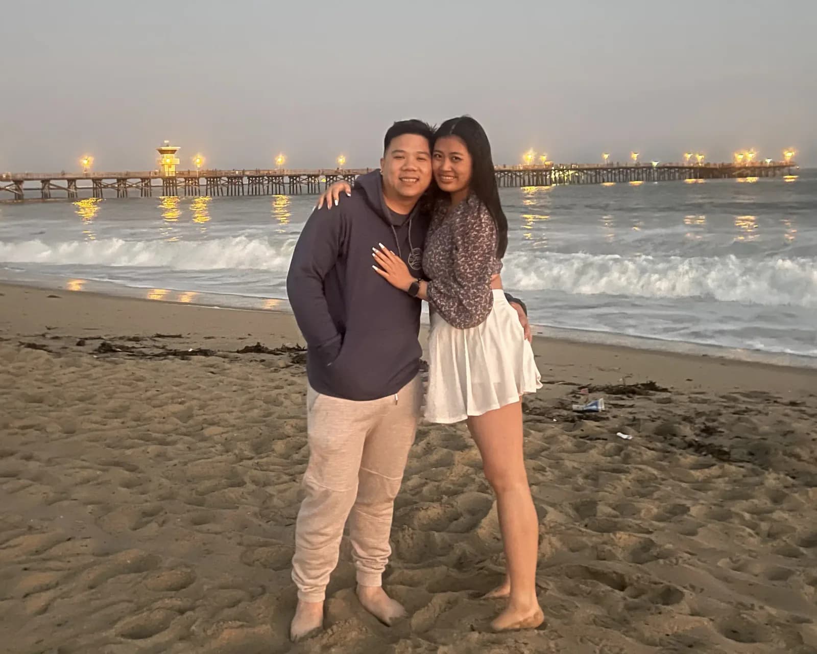 Christine and Thomas standing together on Seal Beach at dusk