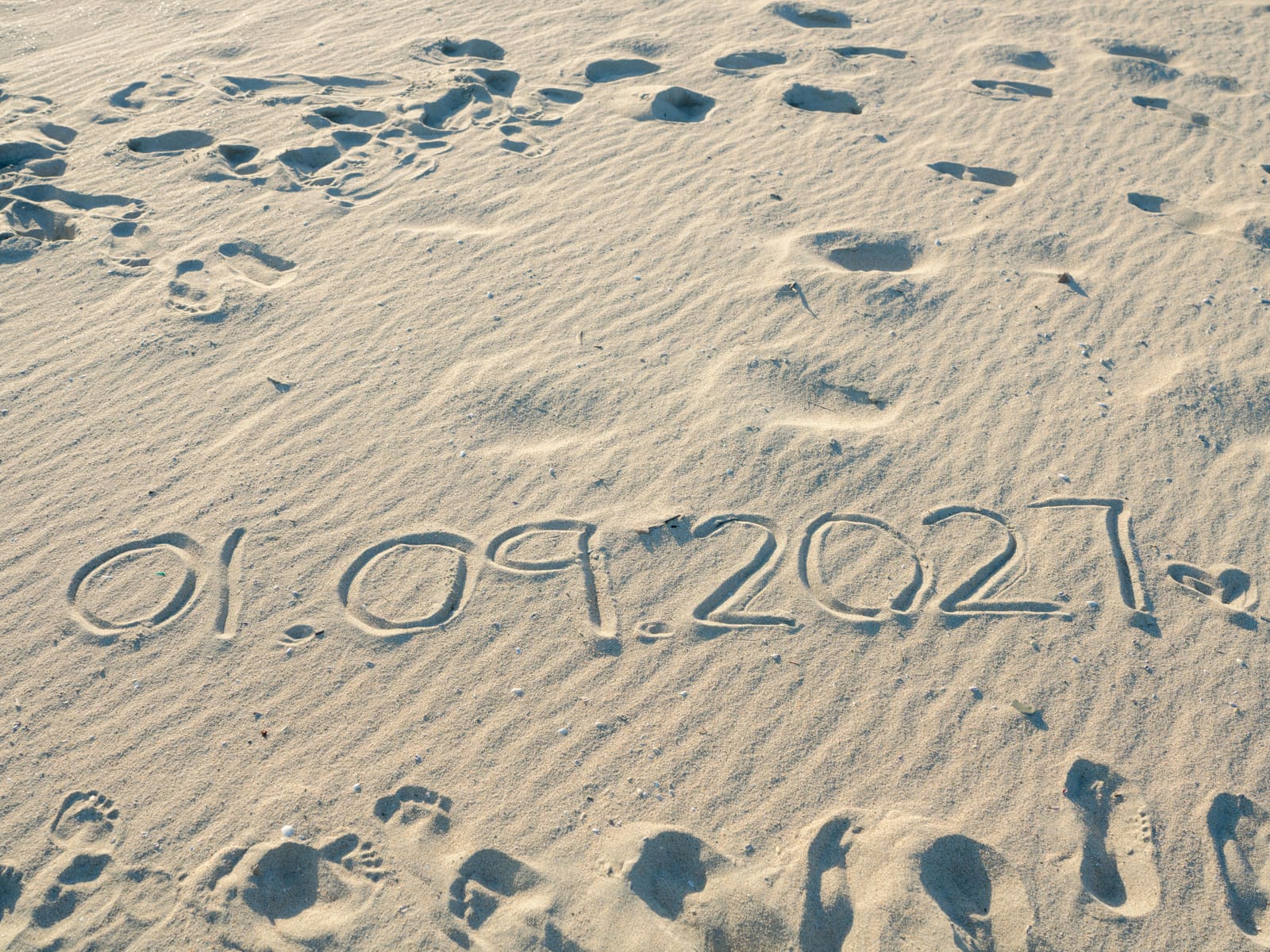 “01.09.2027” written in the sand.