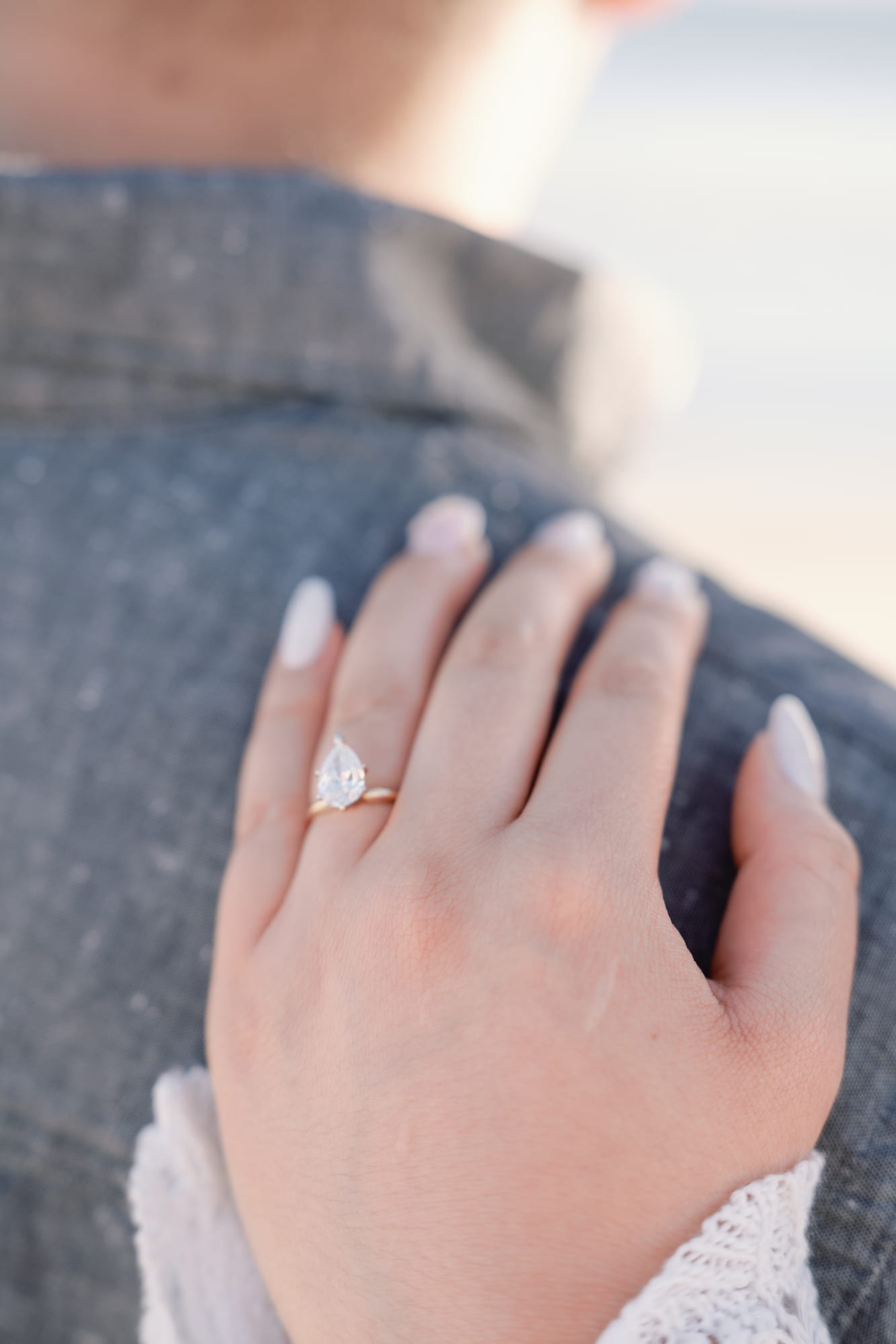 Christine's engagement ring, her hand resting on Thomas's shoulder.