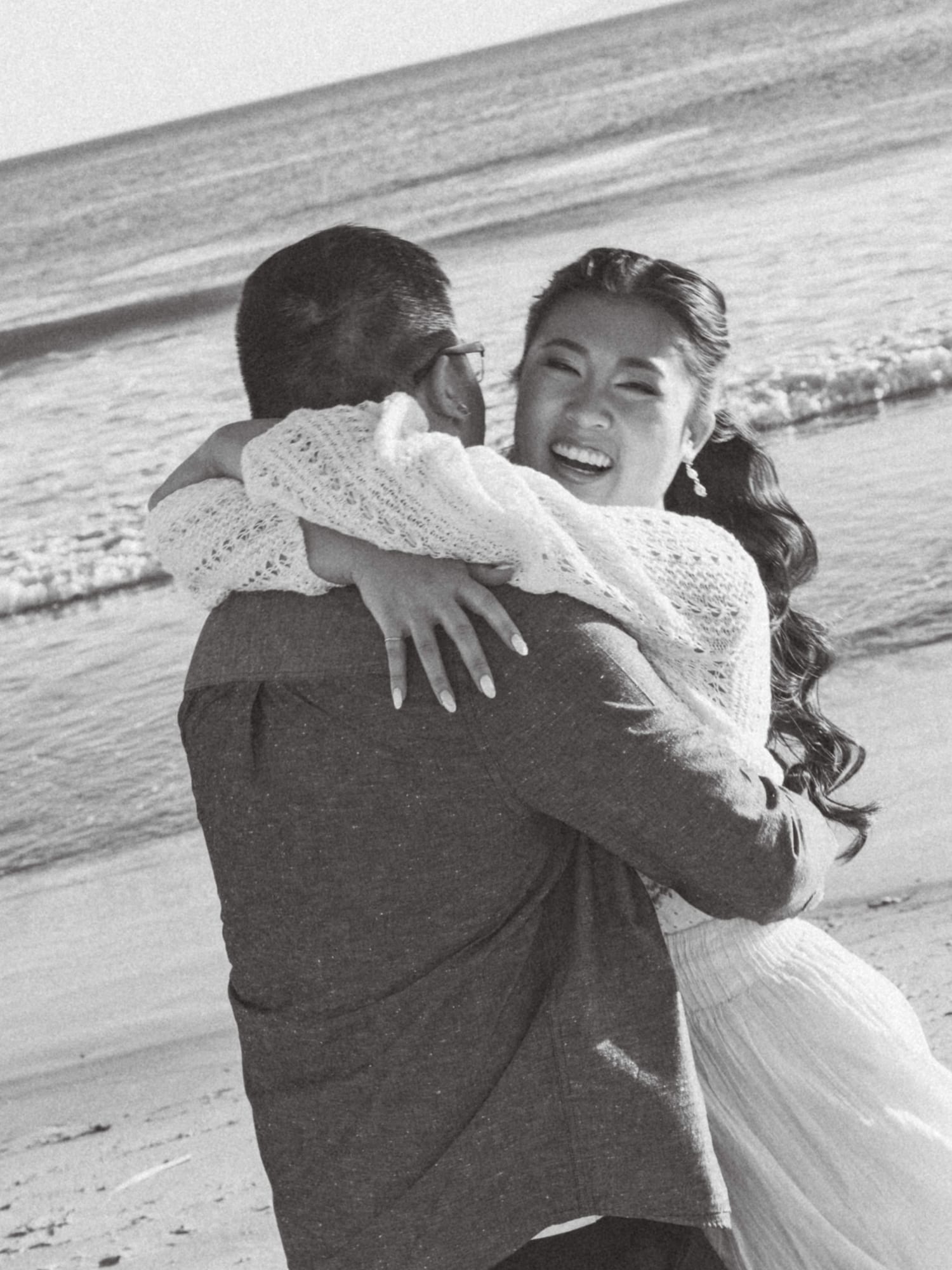 Thomas lifting Christine as they laugh, in black and white.
