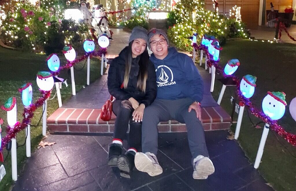 Christine and Thomas surrounded by Christmas lights.